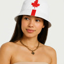 Woman wearing a white bucket hat with a red maple leaf design on a plain background